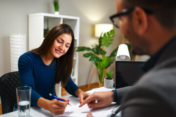 Young woman signing contract during a business meeting with a businessman
