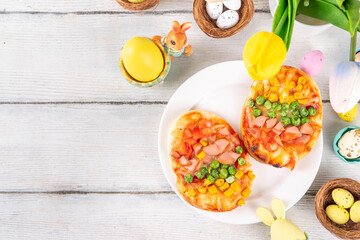Cute Easter pizza for children brunch or party, pizza with  in form of bunny head and Easter eggs, with vegetables, cheese and tomato sauce, 