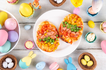 Cute Easter pizza for children brunch or party, pizza with  in form of bunny head and Easter eggs, with vegetables, cheese and tomato sauce, 