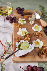creative cheese board serving with soft mold cheese, pistachio honey, white wine and floral decoration on green background