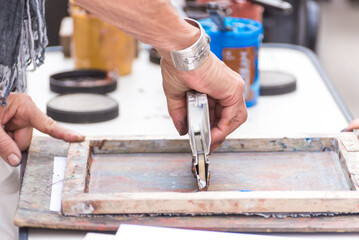 close up of hands using a spatula painting an engraving, art, culture