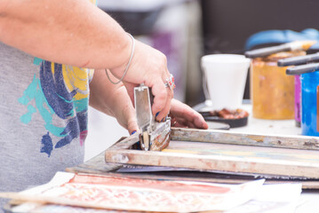 close up of hands placing paint for wood engraving, press, art