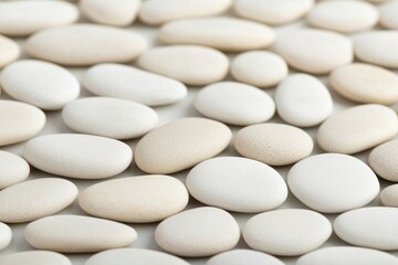 Fototapeta premium A collection of smooth, white pebbles arranged closely together, showcasing various shapes and sizes, creating a serene and calming visual effect.