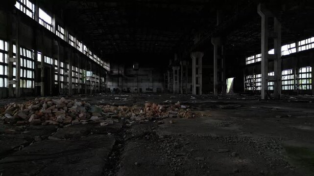Large empty factory hall in decay with shattered glass and debris