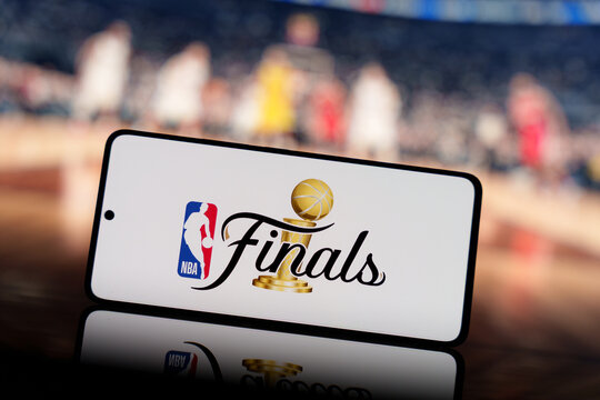 Smartphone displaying NBA Finals logo with a blurred basketball court and players in the background. Basketball championship and sports event concept