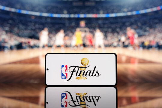 Smartphone displaying NBA Finals logo with a blurred basketball court and players in the background. Basketball championship and sports event concept