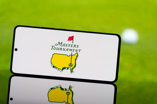 Smartphone displaying Masters Tournament logo with a blurred golf ball and green field in the background. Professional golf championship concept