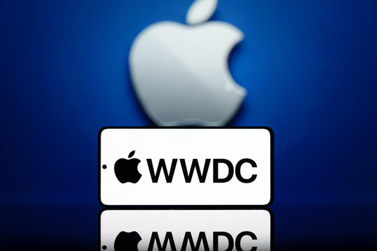 Smartphone displaying WWDC logo with a blurred Apple logo in the background. Apple developer conference and technology event concept