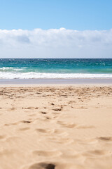 Gentle waves lap against soft sandy shores under a bright blue sky