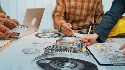 A group of engineers collaborates on detailed technical drawings and blueprints in a bright office,...