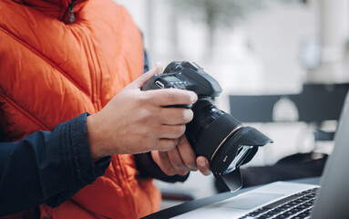Photographer reviewing photos on professional camera and laptop, working on photo editing and post production