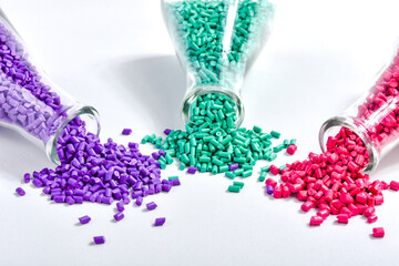 Red, purple and turquoise masterbatch granules in Erlenmeyer flask isolated on white background,...
