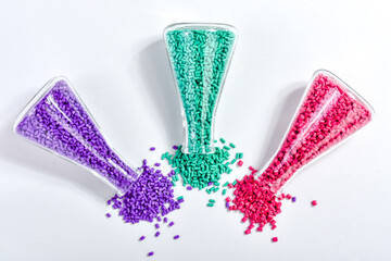 Red, purple and turquoise masterbatch granules in Erlenmeyer flask isolated on white background,...