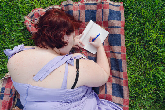 Social media image of a plus-size woman in the park writing in her diary