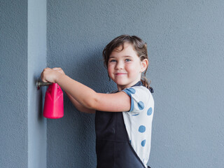 Young girl fills red watering can at a water tap