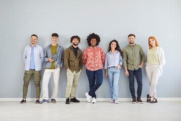 Group portrait of a multinational team of positive people standing together on a gray background. Community crowd, diversity, and unity within a happy and supportive group setting.