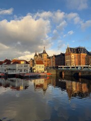 A scenic canal in Amsterdam, Netherlands, with historic Dutch buildings lining the waterfront.