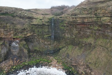Coastal waterfall plunging into sea from cliffs between Scarborough and Whitby.