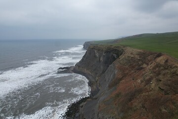 Coastal waterfall plunging into sea from cliffs between Scarborough and Whitby.