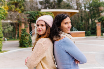 Naklejka premium Mother and daughter standing back to back in park. concept of powerful women