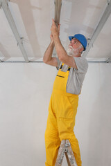 Senior adult worker fixing aluminum batten for gypsum ceiling