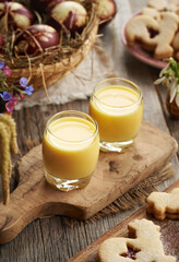 Two glasses of Eiecognac with Easter eggs, spring flowers and cookies