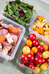 food containers with meat, cheese, tomatoes and herbs on the table top view