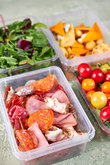 food containers with meat, cheese, tomatoes and herbs on the table top view