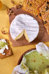 soft white mold cheese with pistachio honey and bread is on the yellow table 