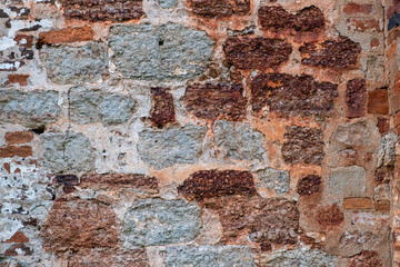 Close-up of a section of a historic stone wall showing different textures and colors.