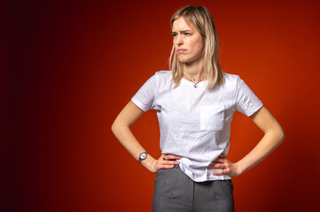Young woman in white t-shirt making disgusted facial expression, surprised, holding hands on hips...