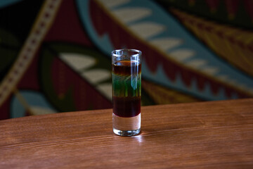 Vibrant Layered Cocktail in a Shot Glass on Wooden Table