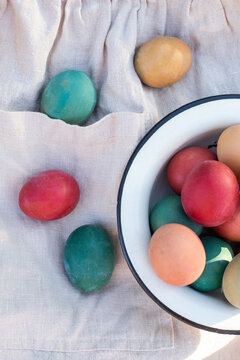 Vibrant dyed eggs on apron and enamel bowl for Easter decor