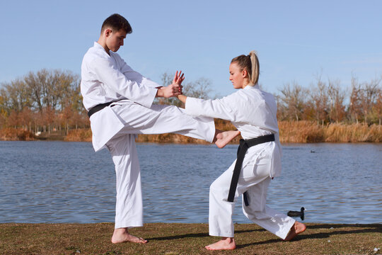 Karate practitioners in white karategi showcase skills by lake