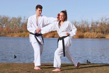 Karate practitioners sparring beside tranquil lake scenery