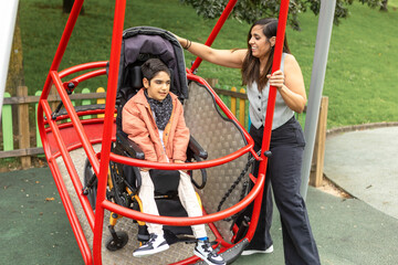 Child with cerebral palsy in wheelchair enjoying accessible park swing