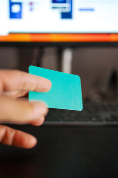 Person Holding a Blank Card in Front of a Computer Screen