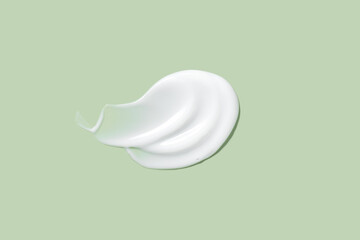Cream smear on mint green background, shot from above