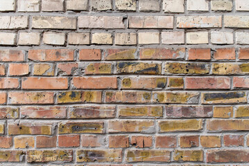 Naklejka premium Worn brick wall with yellow and red hues