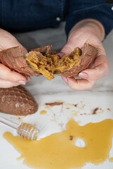 Confectioner holding an Easter egg and showing the filling of a Brazilian honey cake_top view_vertical.