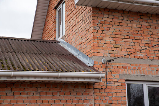 Corner of a brick house with a wavy roof and a metal apron
