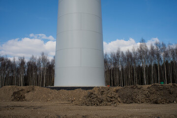 A large white tower with dirt and trees in the background.  The concept of green energy construction