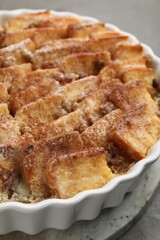 Delicious bread pudding with raisins and cinnamon on grey table, closeup
