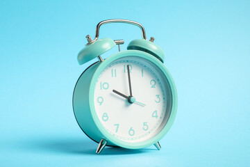 One turquoise alarm clock on light blue background