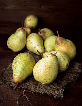 Fresh pears displayed on rustic burlap against wooden background