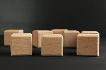 Blank wooden cubes on black table, closeup