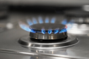 Gas burner with blue flame on stove, closeup