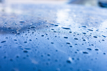 Water droplets accumulate on a blue surface after car wash during the early morning hours