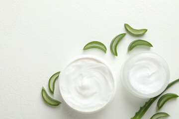 Moisturizing cream with extract of aloe vera and cut leaves on white textured background, flat lay. Space for text