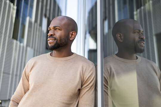 Reflective cuban man in urban setting with modern architecture